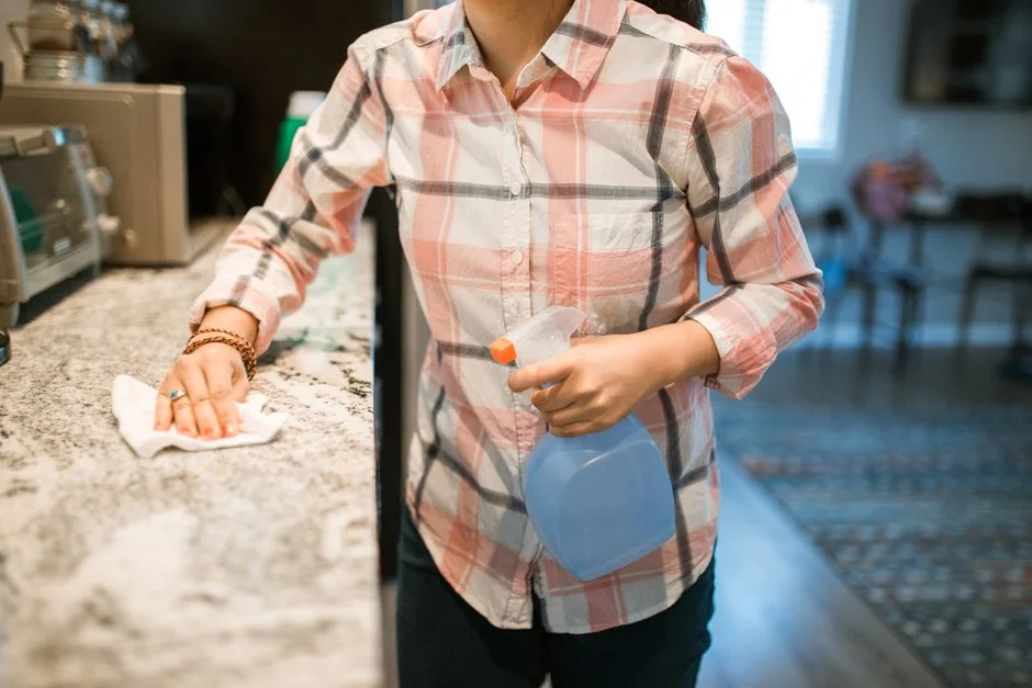 team-02 A woman in overalls cleans a wall in a stylish living room, enhancing home hygiene.